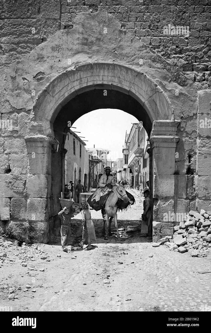 Syrien: Das Osttor von Damaskus (Dimashq) und die 'Straße namens Straight', c. 1950-1977 (außerhalb des Urheberrechts). Die Straße mit dem Namen Straight (lateinisch: Via Recta, arabisch: Al-Shāri` al-Mustaqīm) ist die römische Straße (Decumanus Maximus), die von Osten nach Westen in der Altstadt von Damaskus verläuft. Es wurde von St. Paul besucht, wie in der Apostelgeschichte, dem fünften Buch des christlichen Neuen Testaments, aufgezeichnet, und enthält mehrere interessante Sehenswürdigkeiten aus der römischen, christlichen und islamischen Zeit. Das östliche Ende der Straight Street befindet sich am Bab al-Sharqi, dem römischen Tor der Sonne Stockfoto